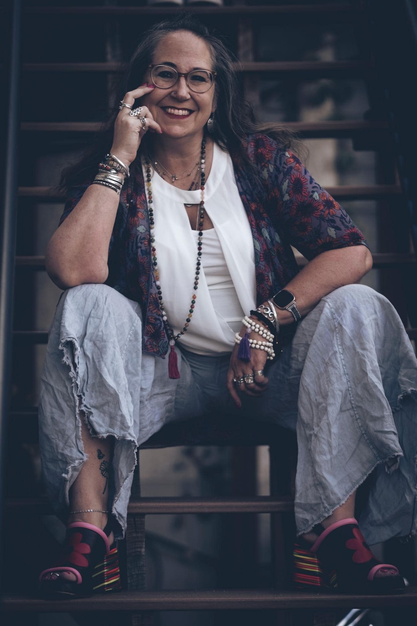 Author Jessica stokes sitting in a chair. She is relaxed and smiling with her chin resting in her right hand.