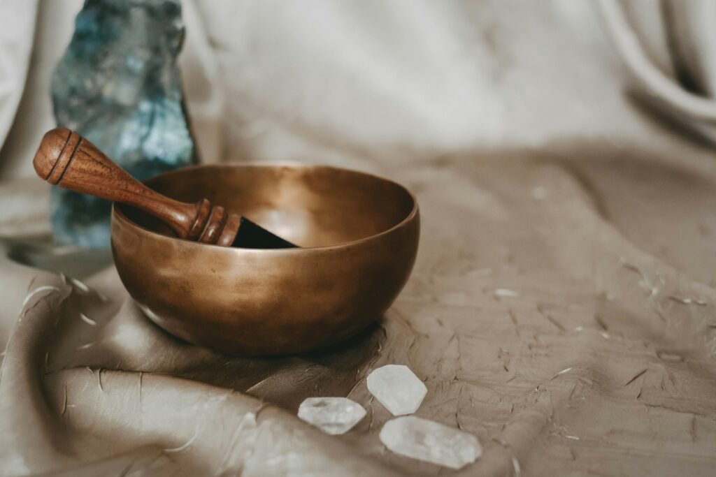 A gold singing bowl for sound healing on gold fabric with labradorite and quartz crystals.